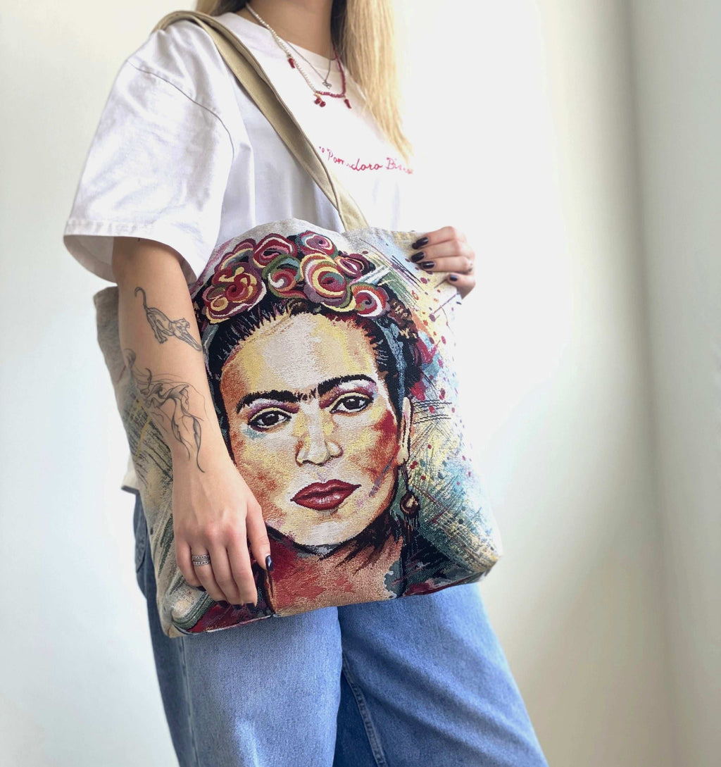 Person holding a tote bag with a colorful portrait design.