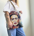 Person holding a tote bag with a colorful portrait design.