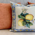 Decorative pillow with lemon design and floral elements on a textured surface.
