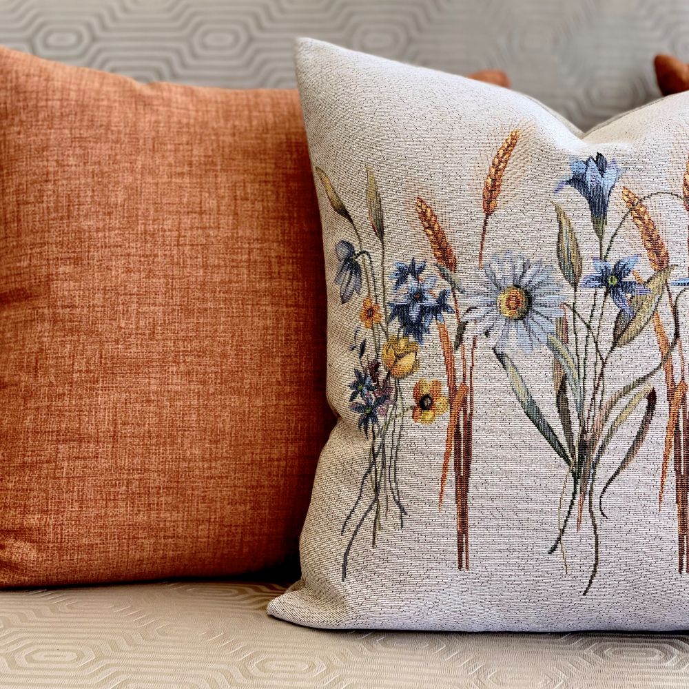Decorative pillow with floral pattern next to a plain brown pillow on a neutral background
