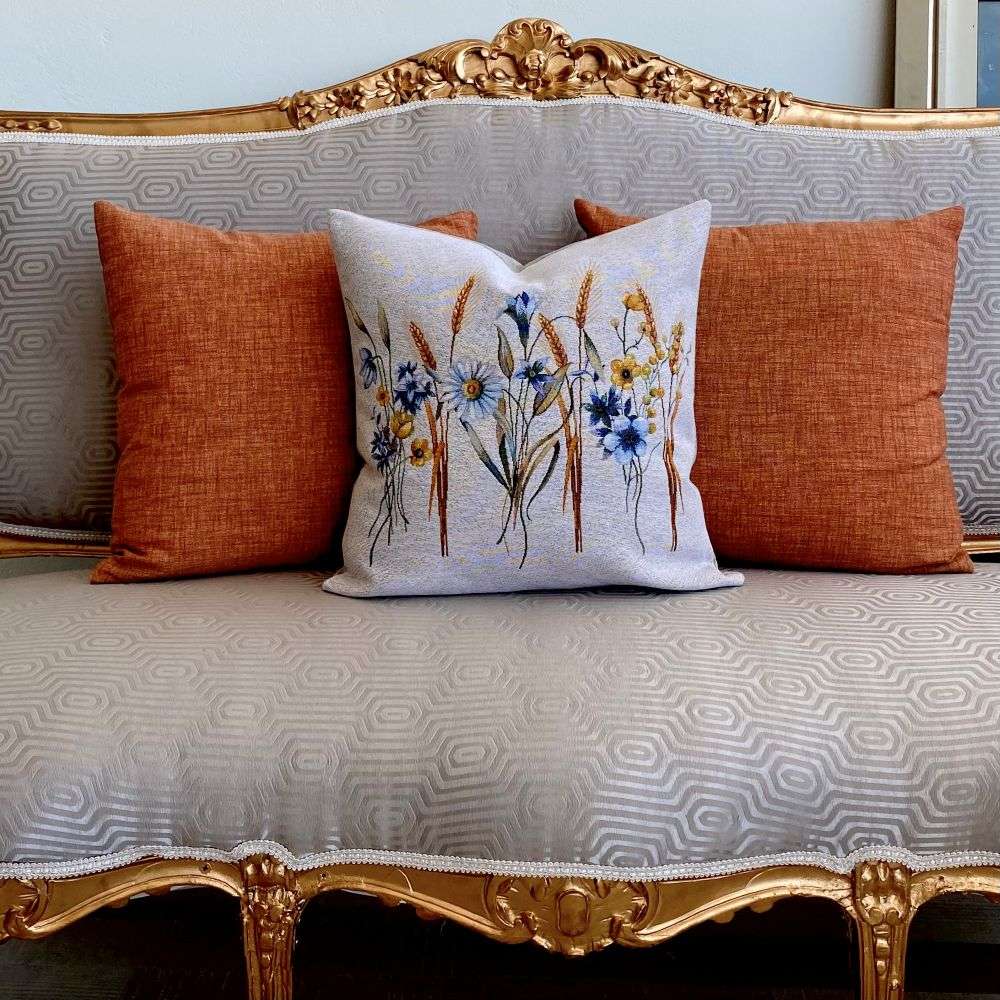 Decorative pillow with floral design on a patterned sofa with orange cushions.