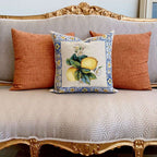 Decorative pillow with lemon design on a patterned sofa with orange cushions.