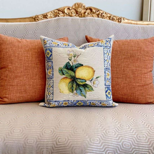 Decorative pillow with lemon design on a patterned sofa with orange cushions.