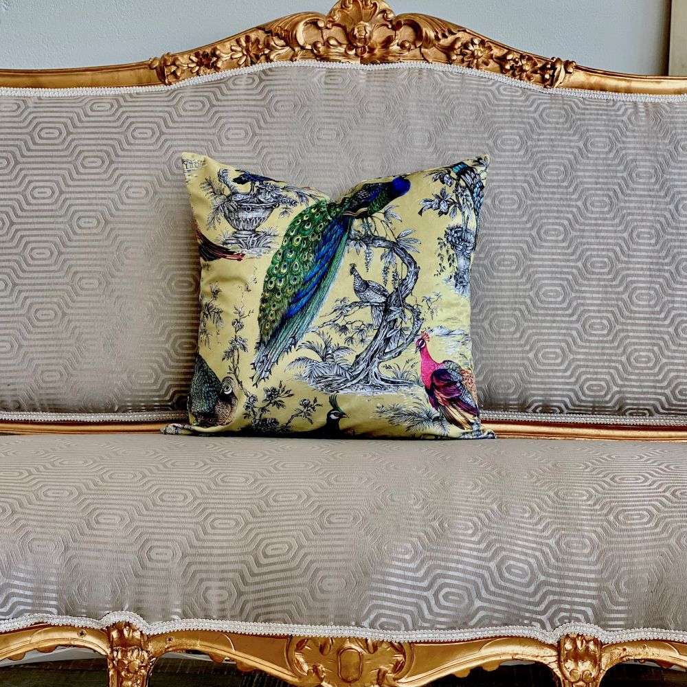 Decorative pillow with peacock design on a patterned sofa