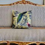 Decorative pillow with peacock design on a patterned sofa