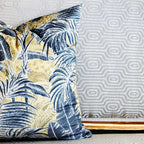 Decorative pillow with blue leaf pattern on a textured wall background