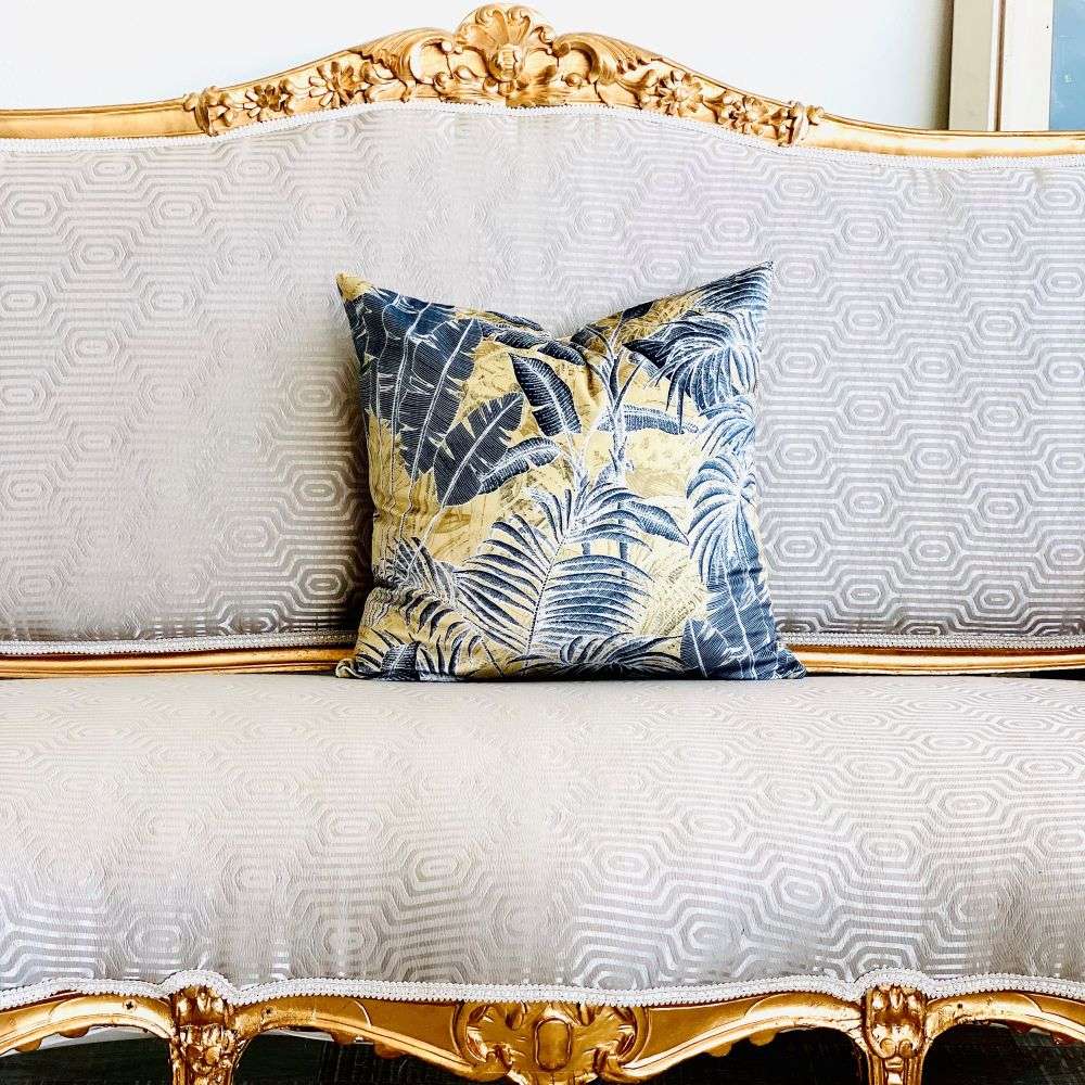 Decorative pillow with leaf pattern on a white sofa with gold trim