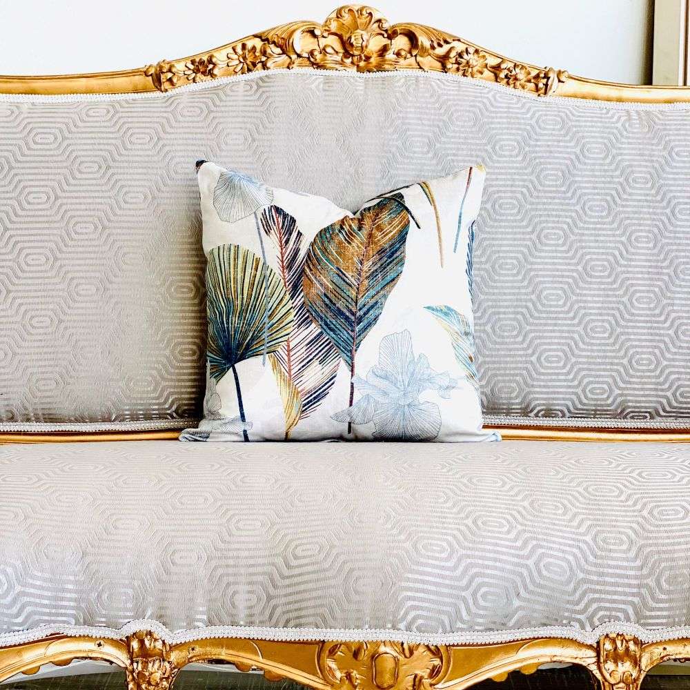Decorative pillow with leaf pattern on a ornate gold and white sofa