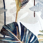 Close-up of a patterned fabric with tropical leaf designs in blue, green, and brown on a neutral background.