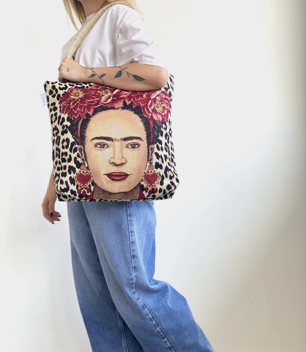Person holding a tote bag with a portrait design featuring a face, flowers, and leopard print.