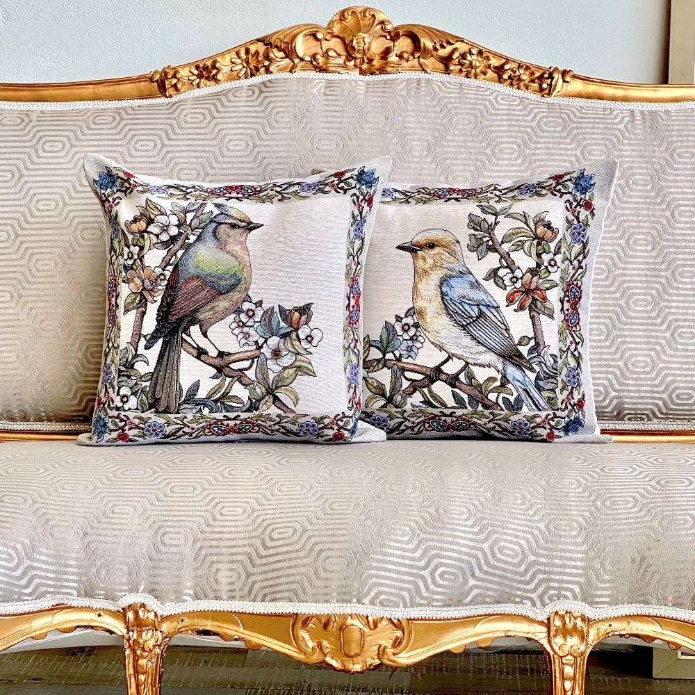Decorative pillows with bird designs on a ornate sofa