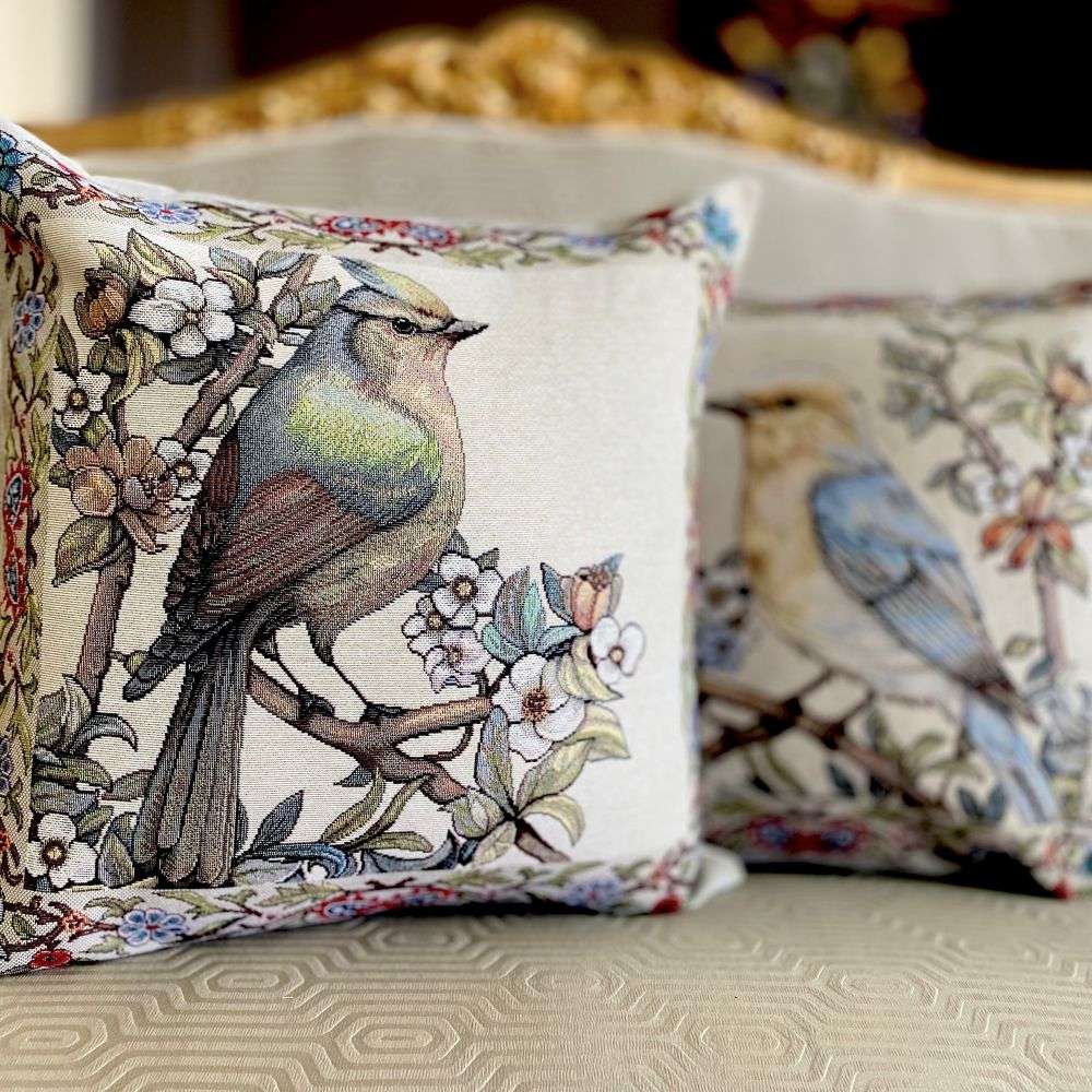 Decorative pillows with bird and floral patterns on a sofa.
