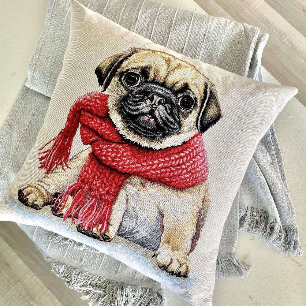 Pillow with a pug dog wearing a red scarf on a textured surface