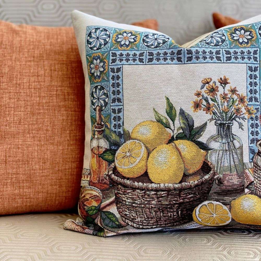 Decorative pillow with a basket of lemons and floral design on a textured surface.