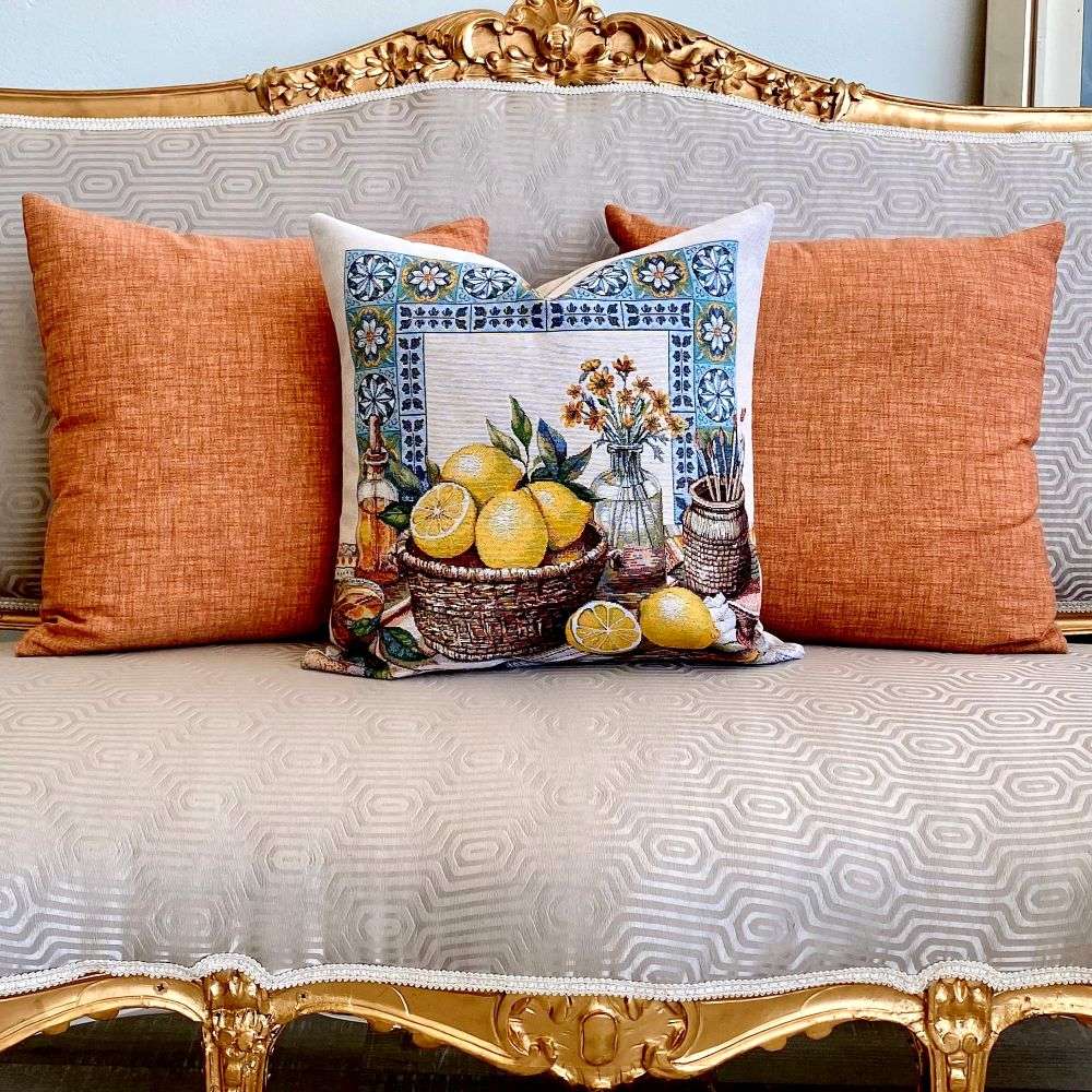 Decorative pillow with lemon design on a patterned sofa with orange cushions