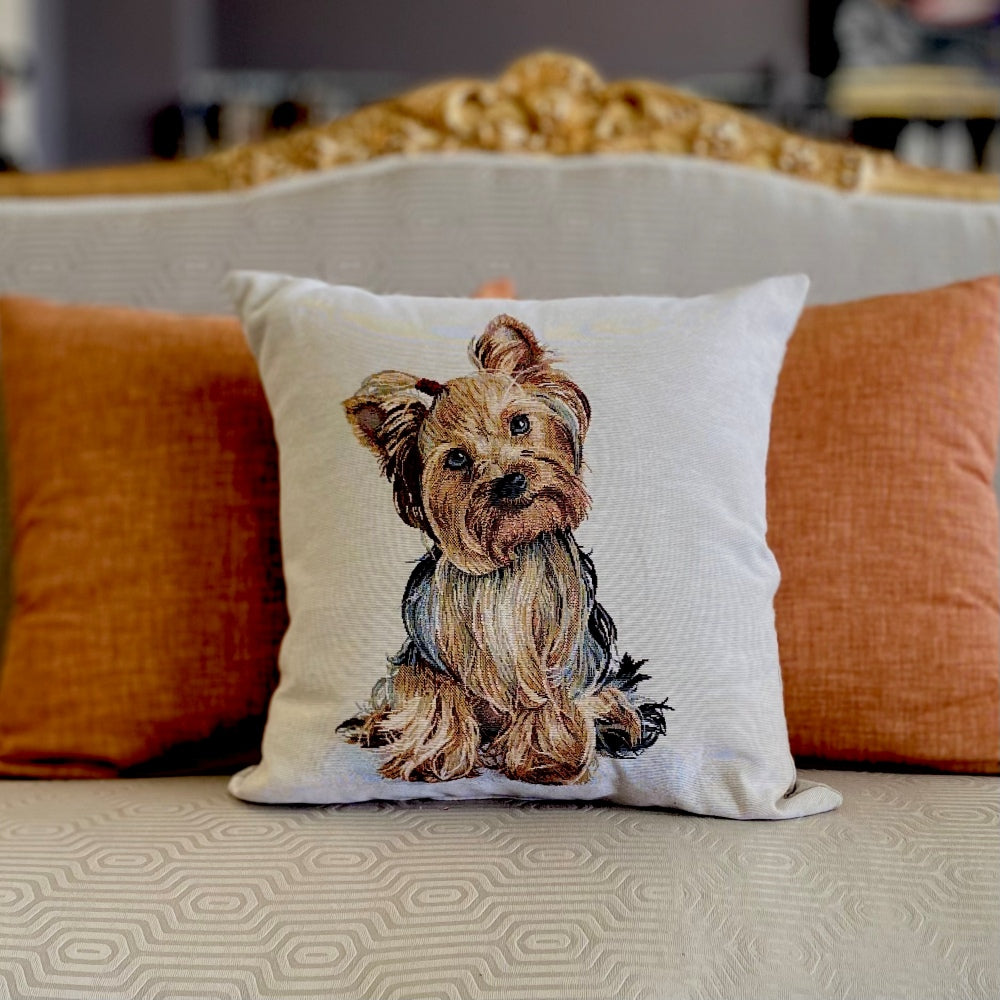 Decorative pillow with a dog illustration on a couch with orange cushions.