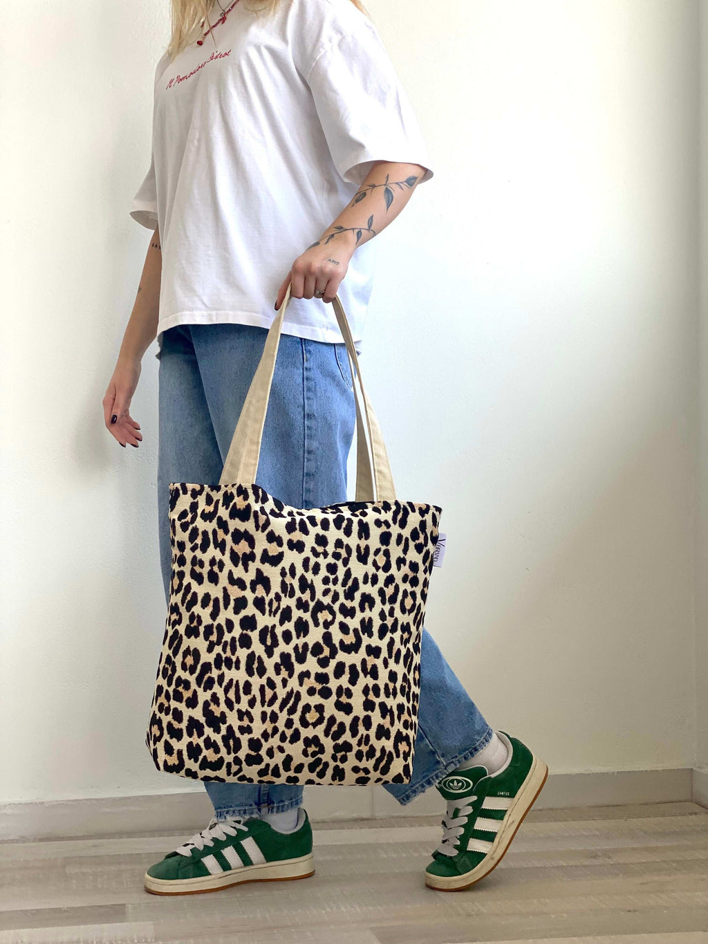 Person holding a leopard print tote bag with a plain background