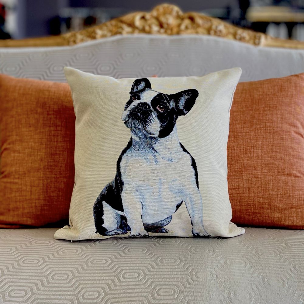 Decorative pillow with a dog design on a couch with orange cushions.