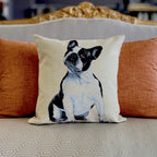 Decorative pillow with a dog design on a couch with orange cushions.