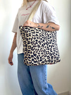 Person holding a leopard print bag against a plain background