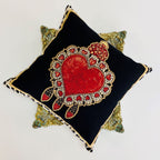 Decorative pillow with a red heart design on a black background