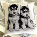 Decorative pillow with embroidered design of two husky puppies on a beige background.