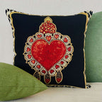 Decorative pillow with a red heart design on a black background, placed on a green cushion.