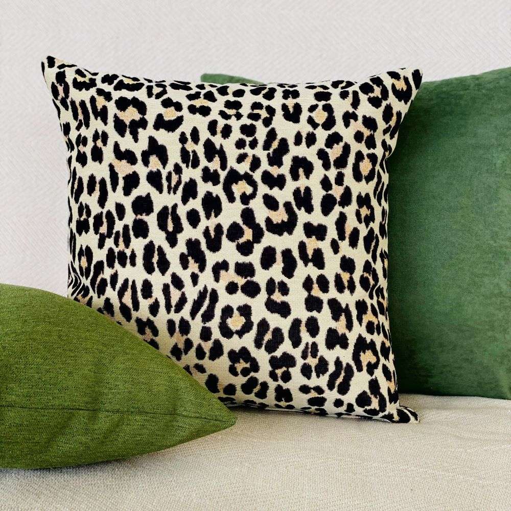 Leopard print pillow with green pillows on a neutral background