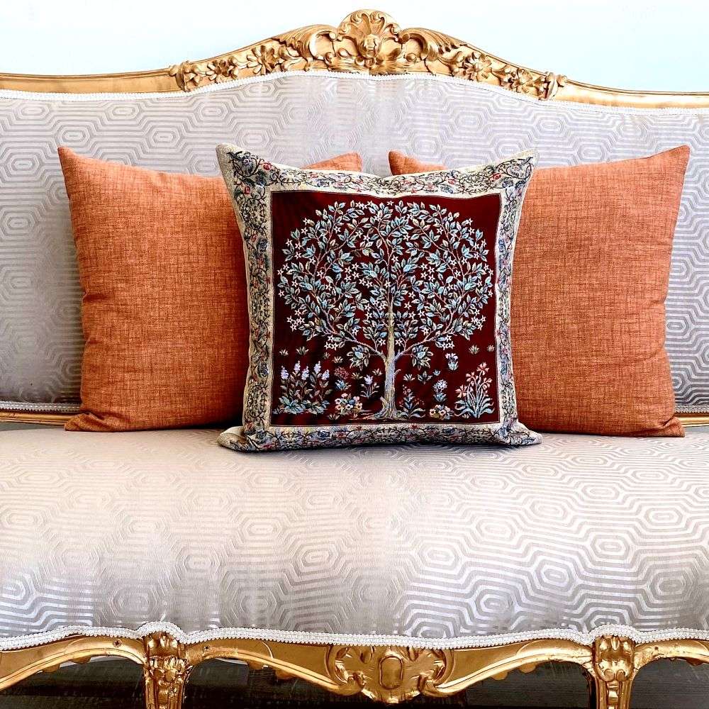 Decorative pillow with tree design on a sofa with orange cushions