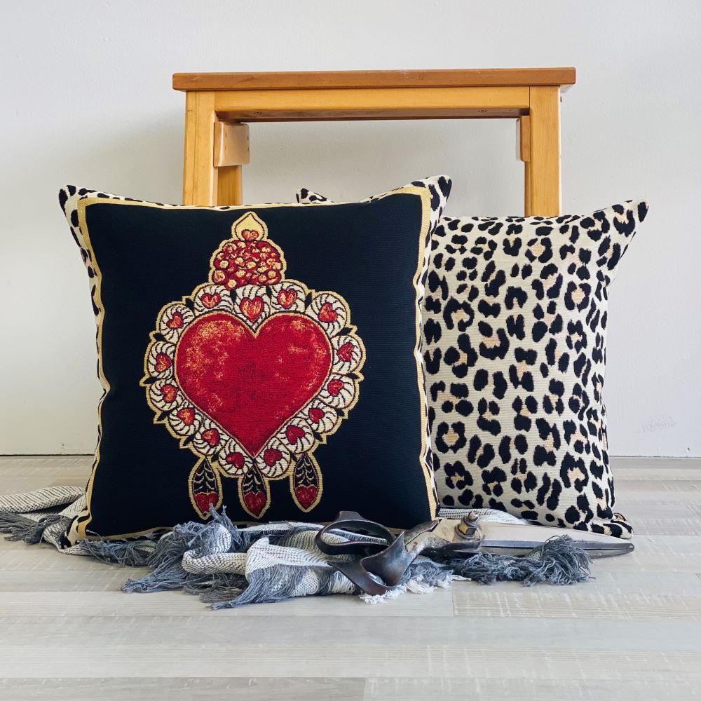 Decorative pillows with a heart design and leopard print on a wooden bench.