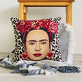Decorative pillow with a portrait design featuring red flowers and leopard print on a wooden surface.