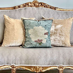 Decorative pillows on a patterned sofa with gold accents