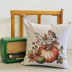 Decorative pillow with pumpkin and bird design next to a vintage radio on a wooden surface.