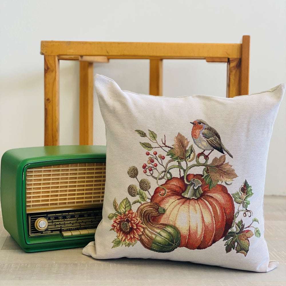 Decorative pillow with pumpkin and bird design next to a vintage radio on a wooden surface.